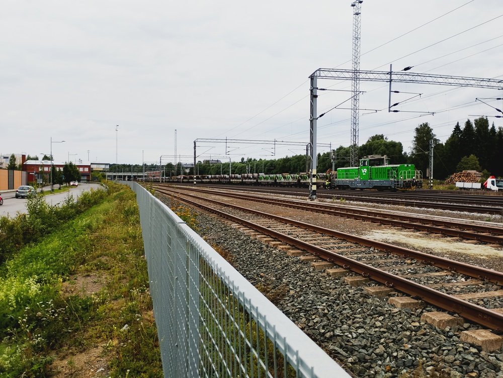 Hämeenlinnan päivystäjä 5.8.2026
Tuskin on Raahen terästehtaan syövereistä saapunut teräskelajuna saatu pysähdyksiin, kun Hämeenlinnan tavara-aseman ovista marssiin päättäväisen oloisesti kaksihenkinen junamiehistö ottamaan haltuunsa Hämeenlinnan päivystyskoneena toimivan Dr19 2844:n, eikä kulu aikaakaan kun veturi on jo teräskelavaunuissa kiinni ja matka jatkuu kohti saman puljun Hämeenlinnan tehdasta. Teräskelavaunut vietiin tehtaalle kolmessa erässä. Junan tuonut Sr3-pari sensijaan karkasi veturijunana Tampereelle.

Avainsanat: op_VR;jt_Vaihtotyö;jyv_Dr19;jyv_ Shmmn-tw;jyv_Shmmns-tw;päivystäjä_Hämeenlinna