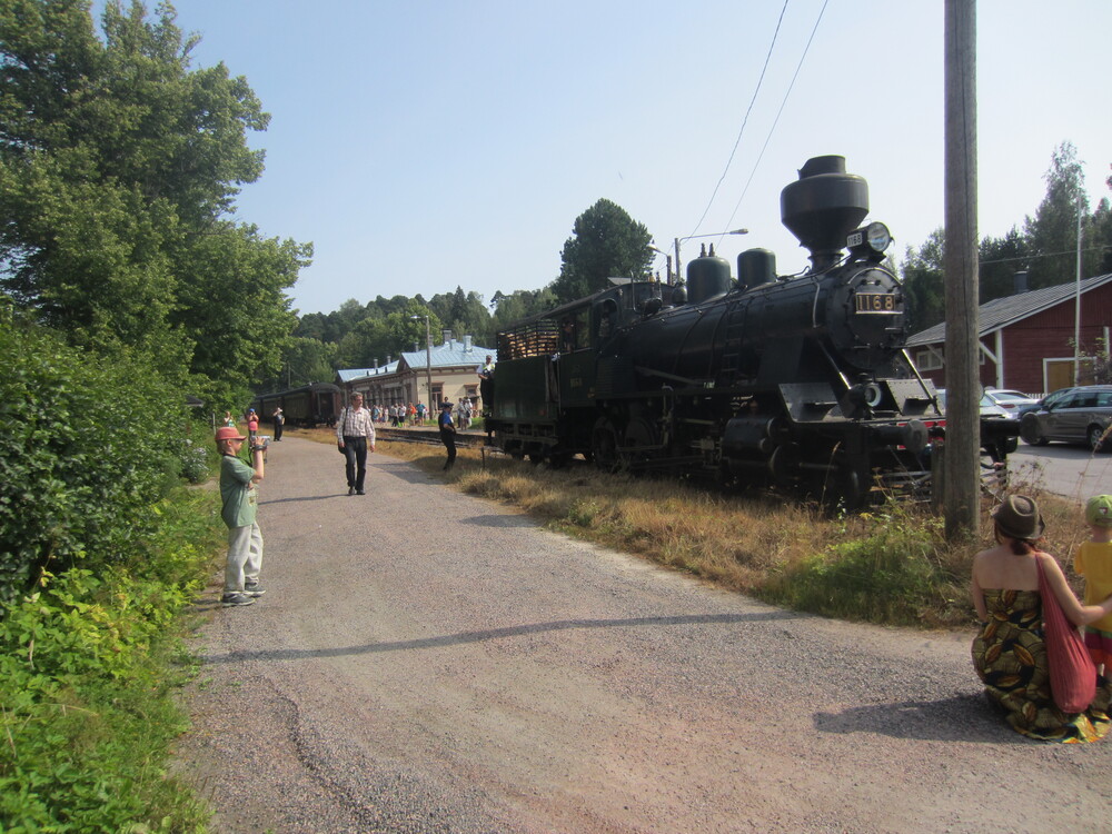 Tk3 1136 vaihtotyön touhussa 2.8.2014
Hetkeä aiemmin Hinthaarasta saapunut Tk3 "Pikku-Jumbo" kiertää vaunuletkan toiseen päähän siirtääkseen ne takaisin makuupaikalleen tavara-aseman eteen, minkä jälkeen raide on vapaa Helsinkiä kohti lähteville lättähatuille.
Avainsanat: op_Steamrail;jyv_Tk3;jyv_Ei_(puukori);museoliikenne;infra_asemarakennus