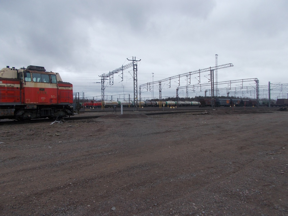 Kouvolan ratapiha 25.4.2018
Dr14 1855 käsittelee idän liikenteen tölkkivaunuja Kouvolasa Dv12 2739:n viettäessä siestaa. Päivystäjän koukussa tuona päivänä olleet vaunut olivat voittopuoleisesti venäläisiä. Vuonna 2018 Venäjän liikenne oli vielä niin vilkasta, että Kouvola oli ääriään myöten täynnä ja vaunuja piti viedä muualle säilöön, kun Kouvolasta oli tila loppu.
VR:n päätös lopettaa Venäjän liikenne vuonna 2022 Ukrainan sodan seurauksena on hiljentänyt Kouvolan ratapihaa huomattavasti.
Avainsanat: op_VR;jt_Vaihtotyö;jyv_Dv12;jyv_Dr14;jyv_Vgobo;jyv_Vtad;jyv_Hkba;päivystäjä_Kouvola
