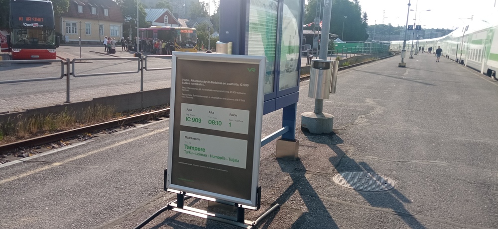Paperinen infonäyttö Turun satamassa
Tusun sataman lähtevien junien näyttö ei ilmeisesti toimi vaan jättää yhden tietyn junan näyttämättä. Hätäratkaisuna paikalle on saapunut näyttöä korvaava paperilappu. Lapun takaa sensijaan löytyy Helsingin junaa korvaava bussi.
