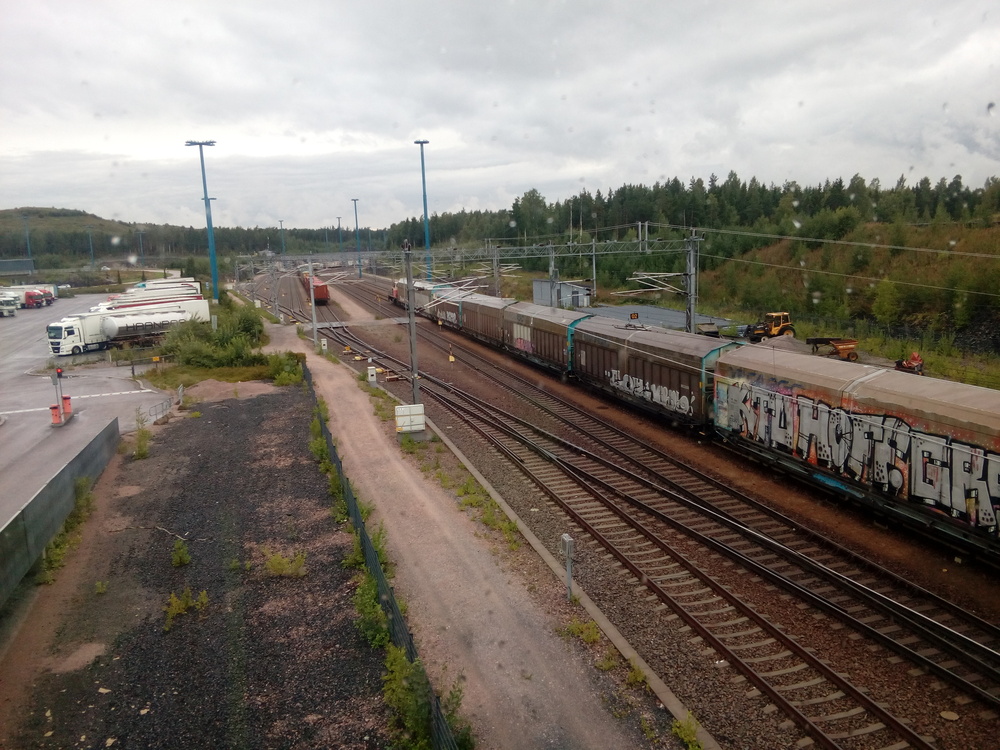 Vuosaaren päivystäjä 25.8.2017 #2
Näkymä porvarinsillalta Vuosaaren ratapihalle. Päivystäjä työntää Vuosaareen saapuneen tavarajunan vaunuja satamaan, jossa ne päätyvät eri kuormausraiteille.
Avainsanat: op_VR;jt_Vaihtotyö;päivystäjä_Vuosaari;jyv_Sim
