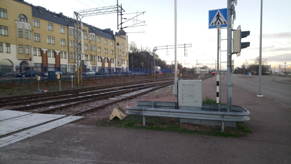Kotkan satamaa 22.11.2018
Kairon kävletien tasoristeys ja tulosuunta Kotkamillsiltä ja ennen myös kantasatamasta Kotkan sataman ratapihalle. Sm2 on taajamajunan ominaisuudessa kääntymässä seisakkeella. Osa raiteista on suljettu liikenteeltä ja niille pääsyn estää kuvassa näkyvä "japaninlippu".
Avainsanat: infra_tasoristeys